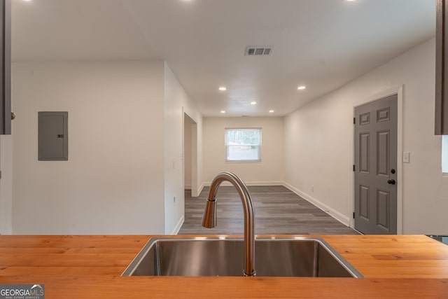 kitchen with electric panel, wood counters, sink, and dark hardwood / wood-style floors