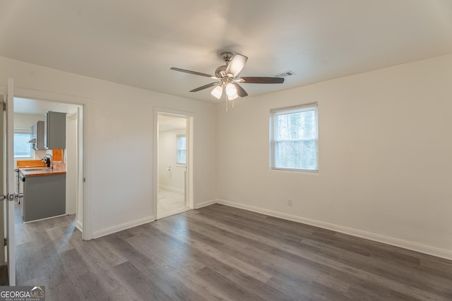 unfurnished bedroom featuring ensuite bathroom, ceiling fan, sink, and dark hardwood / wood-style floors