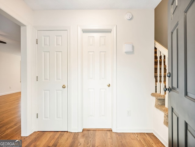 entryway with light wood-style flooring, stairs, and baseboards