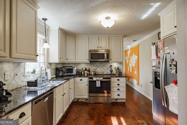 kitchen featuring dark stone countertops, decorative light fixtures, ornamental molding, dark wood-type flooring, and appliances with stainless steel finishes