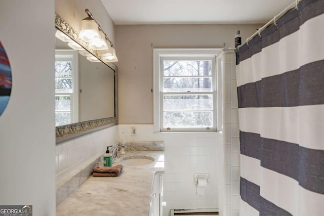 bathroom with a shower with shower curtain, vanity, backsplash, and a healthy amount of sunlight