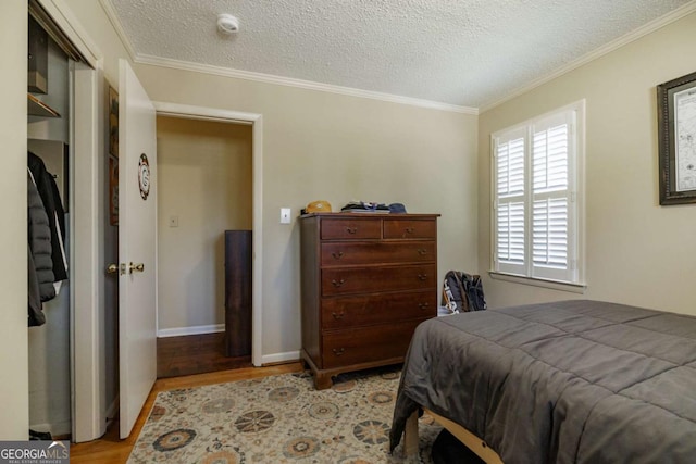 bedroom featuring light wood-type flooring, crown molding, and a textured ceiling