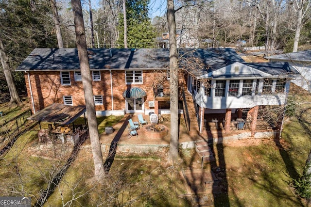 back of house with an outdoor fire pit, a patio, and a sunroom