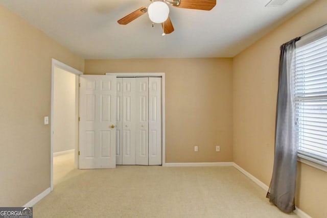 unfurnished bedroom featuring light carpet, ceiling fan, and a closet