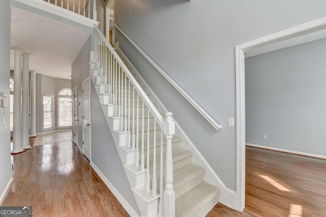 staircase with decorative columns and hardwood / wood-style flooring