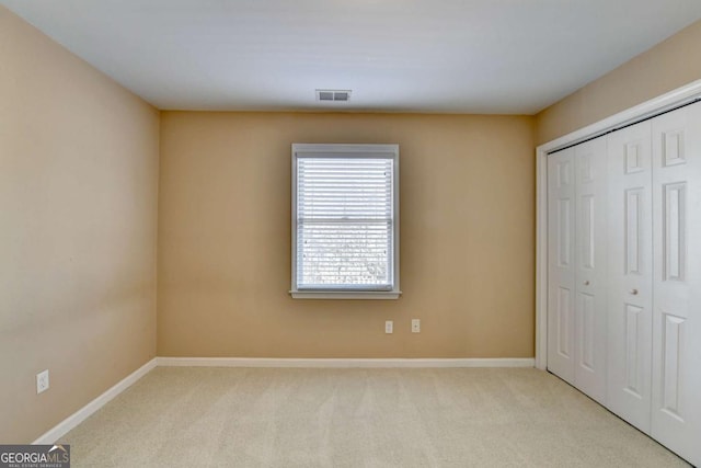 unfurnished bedroom with a closet and light colored carpet