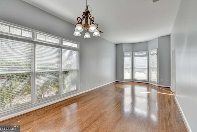 unfurnished room featuring a chandelier and wood-type flooring