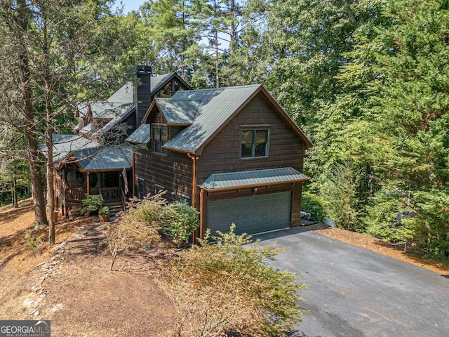 chalet / cabin with metal roof, a porch, and a chimney