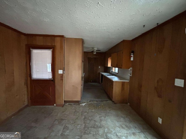 kitchen with sink, wooden walls, a textured ceiling, and ceiling fan