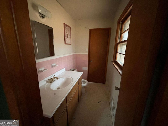 bathroom with tile walls, vanity, and toilet