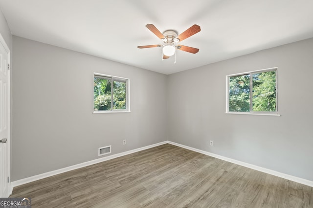 spare room with baseboards, visible vents, ceiling fan, and wood finished floors