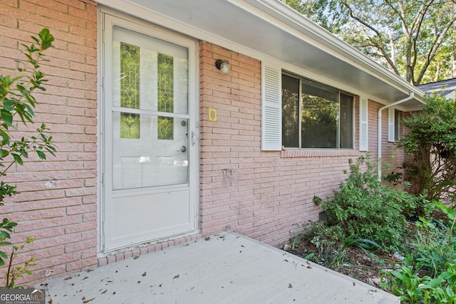 view of exterior entry featuring brick siding and crawl space