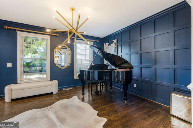 living area with a chandelier, dark wood-style flooring, and a decorative wall