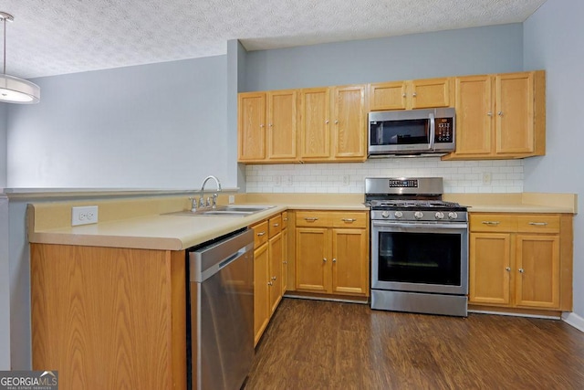 kitchen with dark wood-type flooring, light countertops, appliances with stainless steel finishes, and a sink