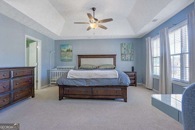 carpeted bedroom with a tray ceiling, a ceiling fan, and baseboards