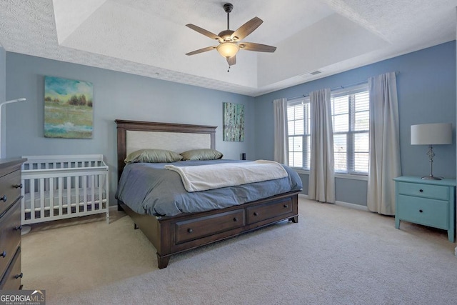 carpeted bedroom featuring ceiling fan, a raised ceiling, baseboards, and a textured ceiling