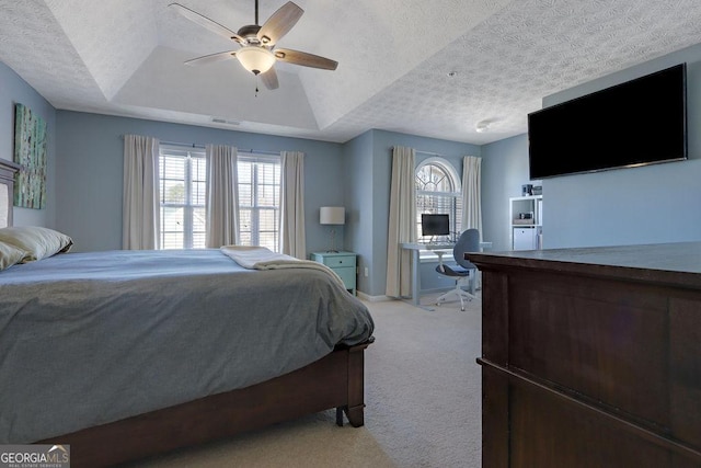 bedroom with visible vents, light carpet, a tray ceiling, a textured ceiling, and ceiling fan