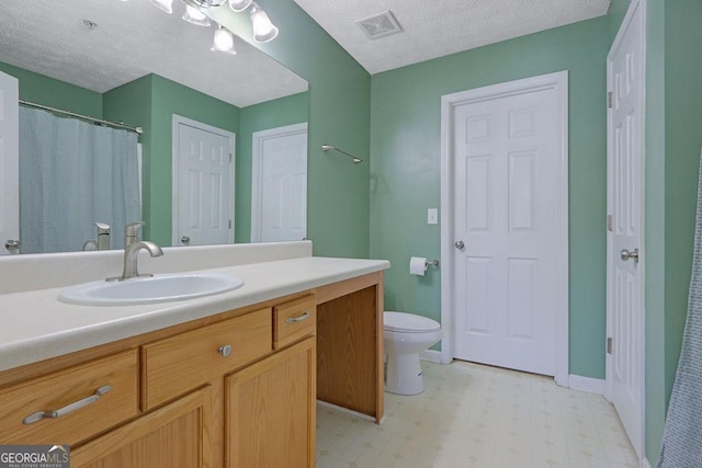 bathroom featuring vanity, visible vents, a textured ceiling, tile patterned floors, and toilet