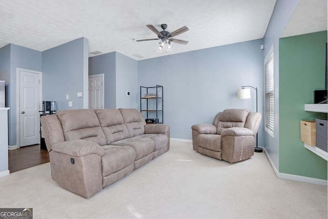 carpeted living area featuring a textured ceiling, baseboards, and ceiling fan