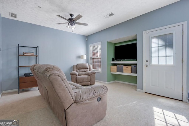 living room with a ceiling fan, visible vents, and a textured ceiling