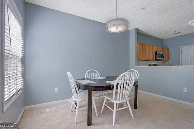 dining area with light colored carpet, visible vents, baseboards, and a textured ceiling