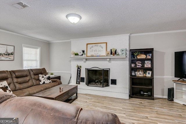 living room with a fireplace, crown molding, a textured ceiling, and light hardwood / wood-style flooring