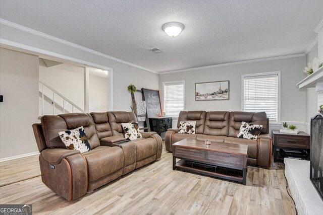 living room with a textured ceiling, ornamental molding, and light hardwood / wood-style floors