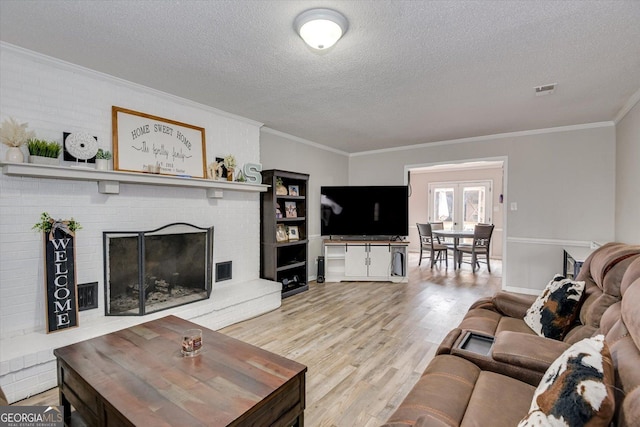 living room featuring light hardwood / wood-style flooring, crown molding, a textured ceiling, and a fireplace