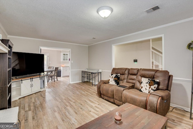 living room with ornamental molding, light wood-type flooring, and a textured ceiling