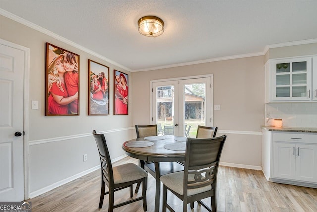 dining room featuring french doors, ornamental molding, and light hardwood / wood-style floors