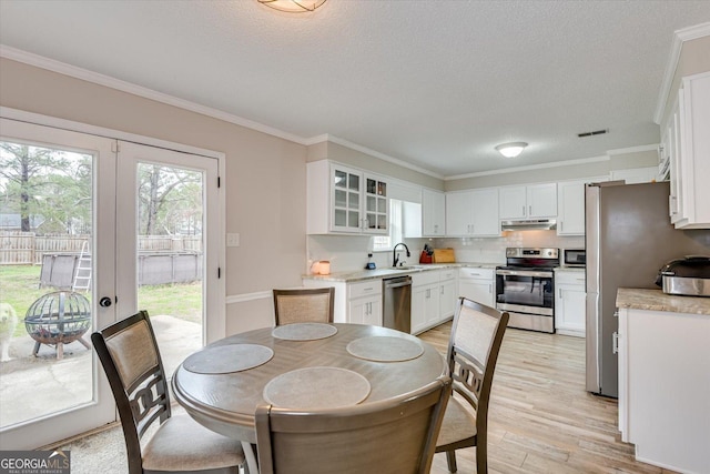 dining area with sink, ornamental molding, and light hardwood / wood-style flooring