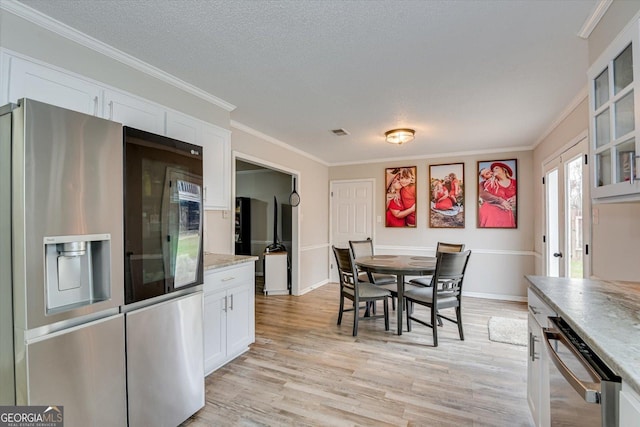 dining room with a textured ceiling, ornamental molding, and light hardwood / wood-style flooring