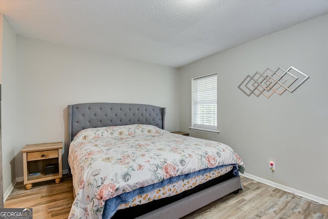 bedroom with a textured ceiling and light hardwood / wood-style flooring