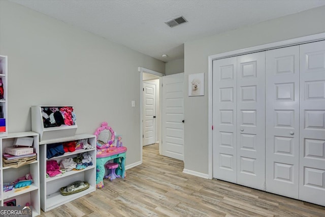 recreation room featuring a textured ceiling and light hardwood / wood-style floors