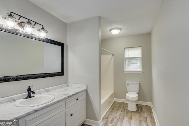 full bathroom featuring bathtub / shower combination, toilet, wood-type flooring, a textured ceiling, and vanity