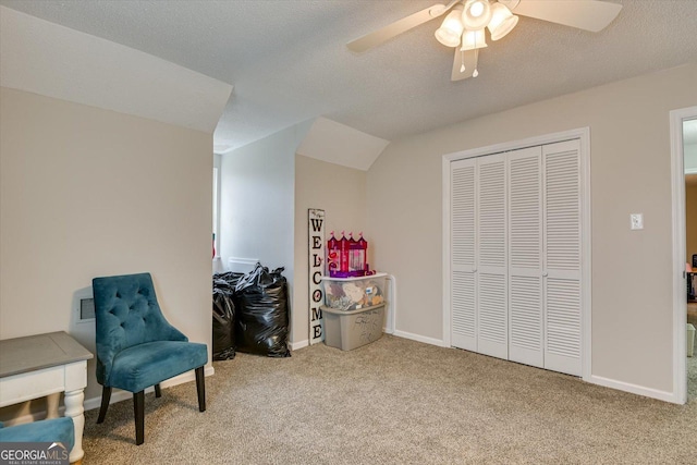 living area featuring ceiling fan, a textured ceiling, and light colored carpet