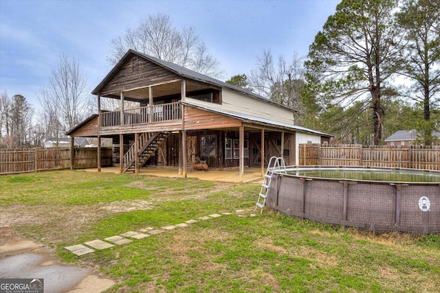 rear view of property with a yard and a fenced in pool