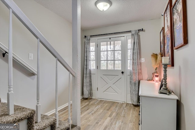 foyer entrance featuring light hardwood / wood-style floors and a textured ceiling