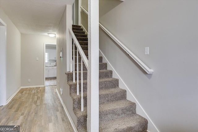 stairway with wood-type flooring and a textured ceiling