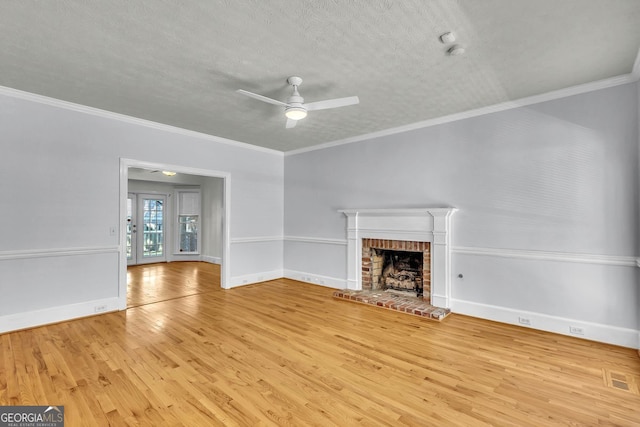 unfurnished living room with hardwood / wood-style flooring, ornamental molding, a brick fireplace, and ceiling fan