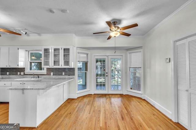 kitchen with decorative backsplash, white cabinetry, ceiling fan, and kitchen peninsula