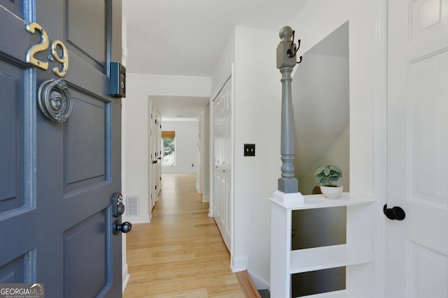 entrance foyer featuring ornamental molding, light wood finished floors, visible vents, and baseboards