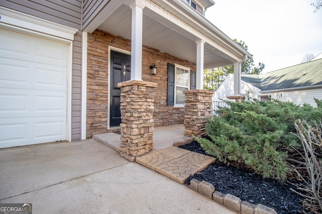 entrance to property with a garage, stone siding, and a porch