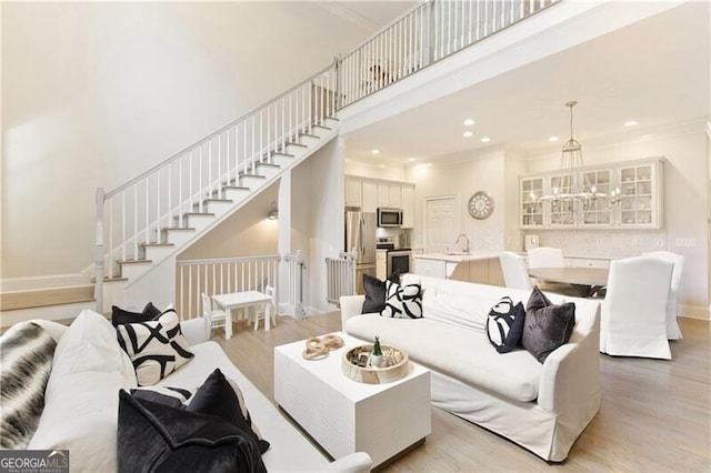 living room featuring light wood-type flooring, sink, and crown molding