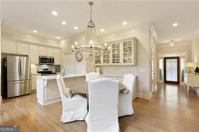 dining room with light hardwood / wood-style flooring, sink, crown molding, and an inviting chandelier