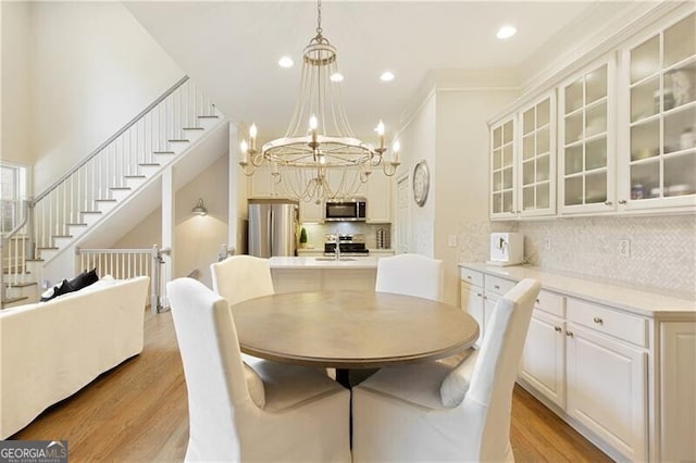 dining room featuring sink, crown molding, a notable chandelier, and light hardwood / wood-style floors