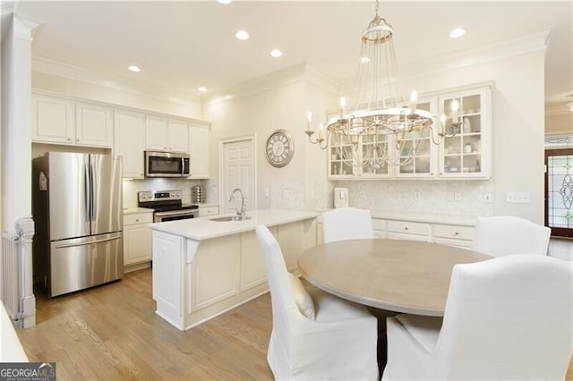 kitchen featuring appliances with stainless steel finishes, sink, light wood-type flooring, pendant lighting, and white cabinets