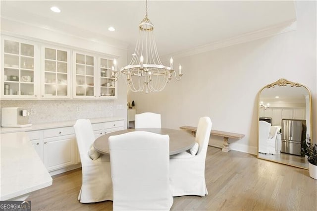 dining space featuring ornamental molding, a chandelier, and light hardwood / wood-style flooring