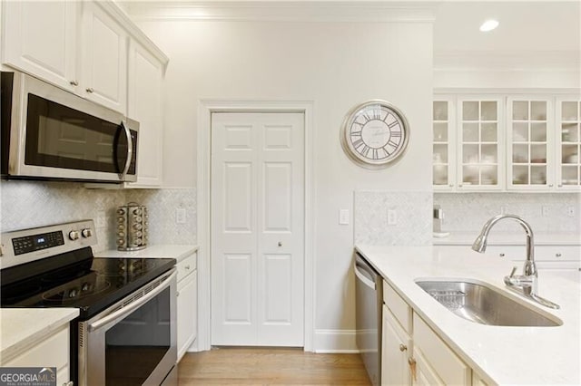 kitchen with ornamental molding, sink, stainless steel appliances, and decorative backsplash