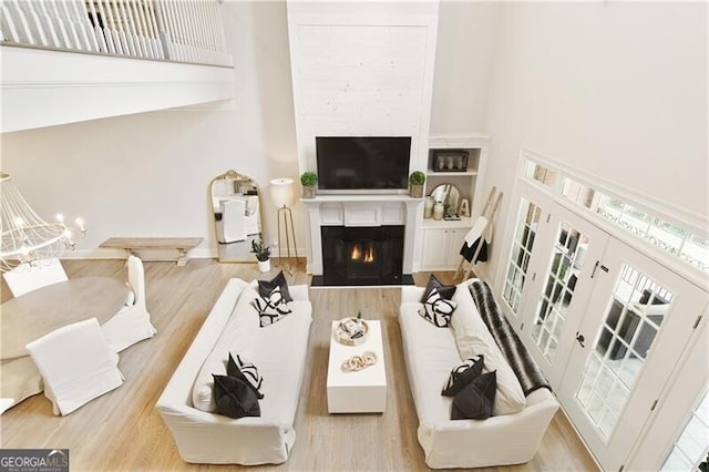 living room featuring light hardwood / wood-style floors, plenty of natural light, and a towering ceiling